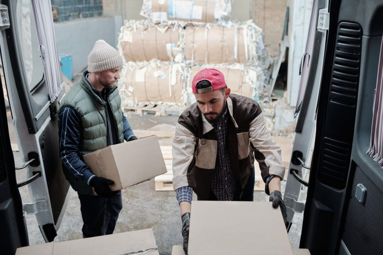 Deux livreurs déchargent des colis d'une camionnette sur un site industriel