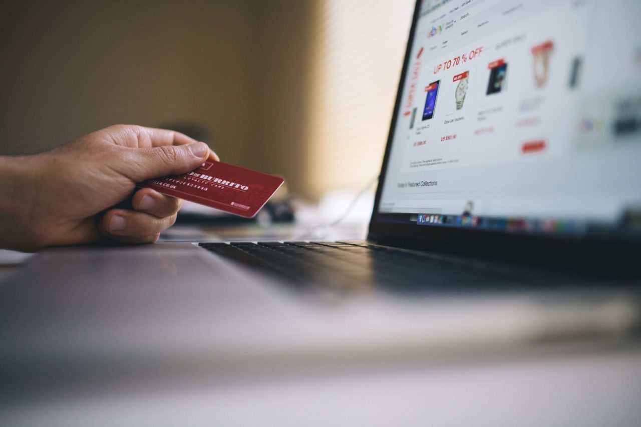 Person holding a credit card while shopping online on a laptop
