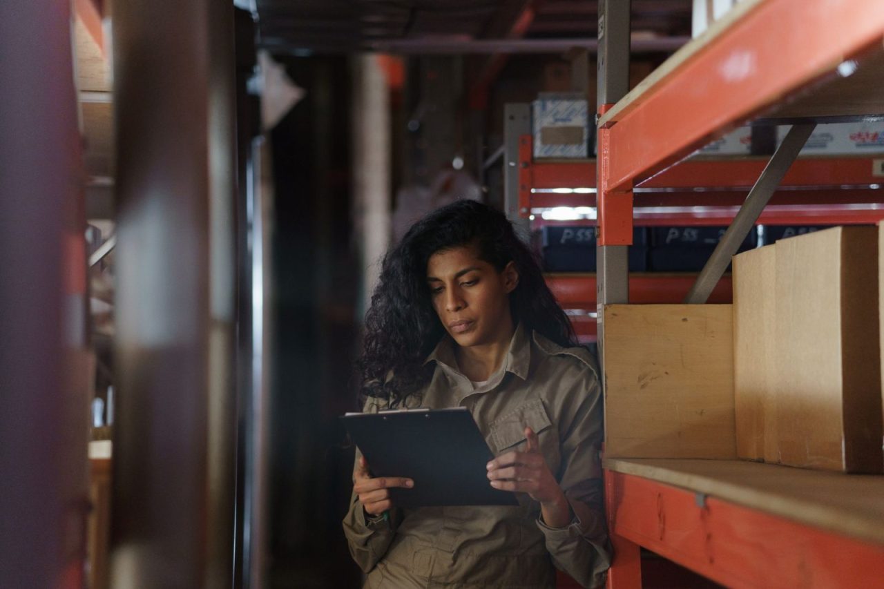 Woman in a warehouse taking inventory with a clipboard