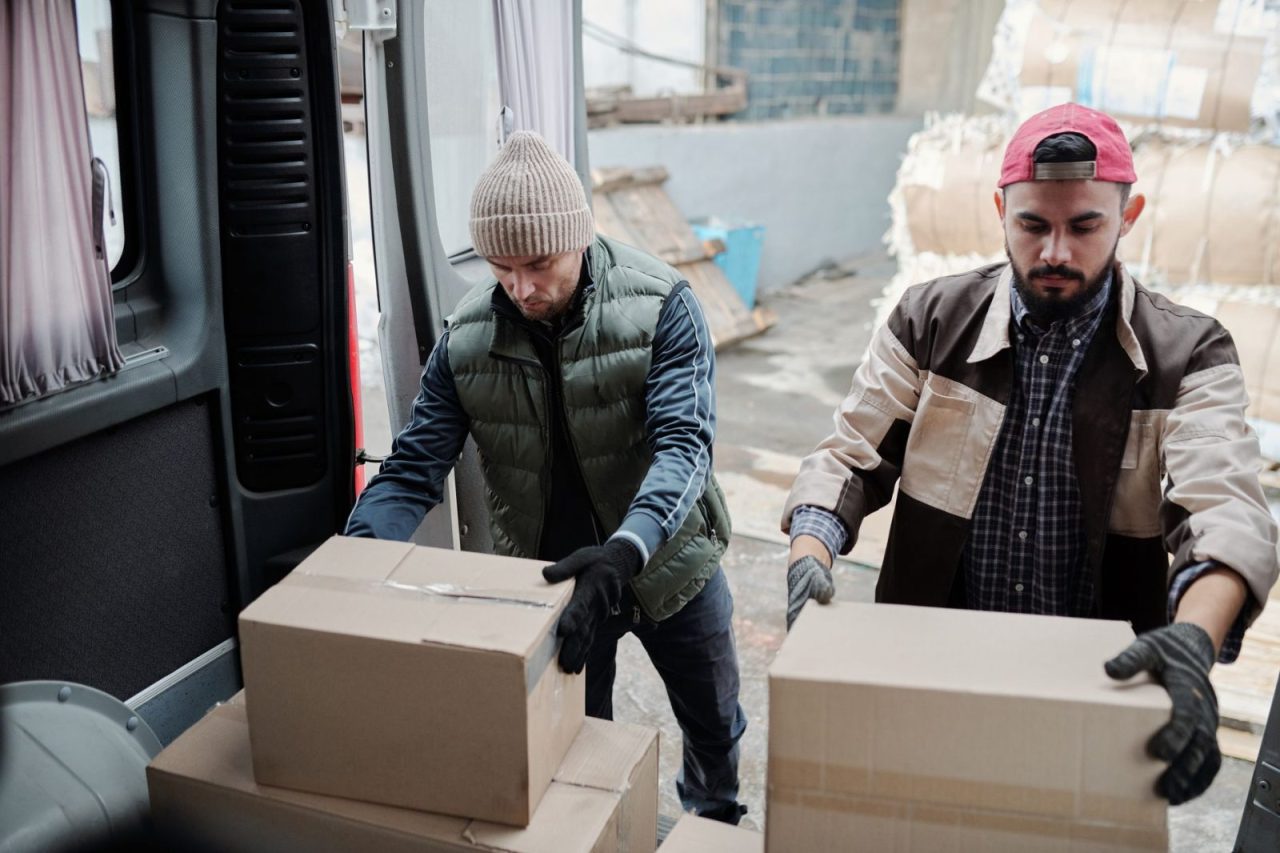 Two workers loading packages into a delivery van, illustrating teamwork in logistics