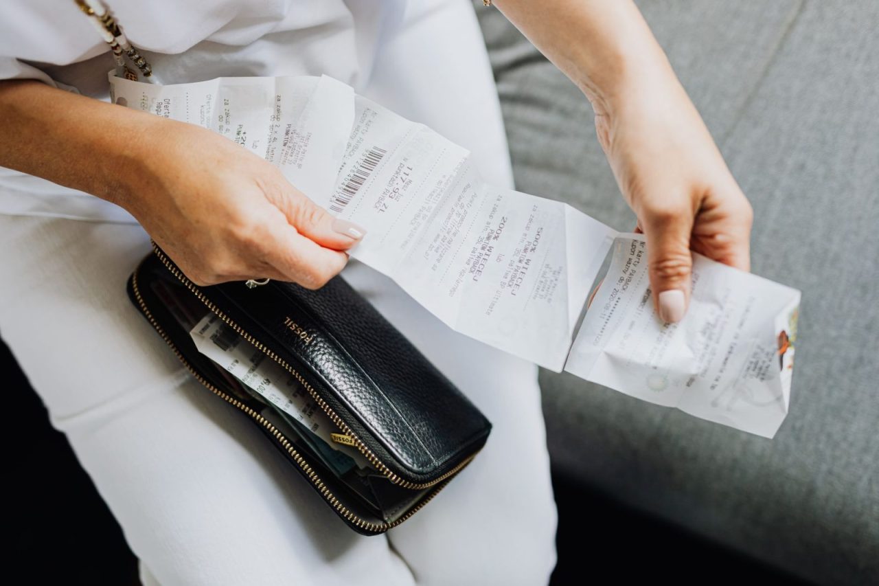 Woman's hands sorting multiple receipts from a black wallet