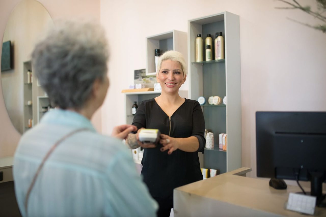 Hairdresser helping a customer complete payment at a salon counter