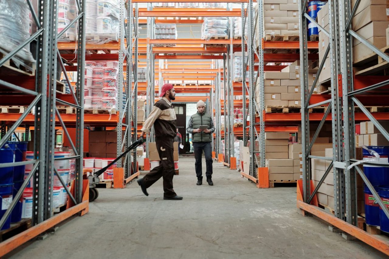 Deux employés gèrent des stocks dans une allée d’entrepôt spacieuse