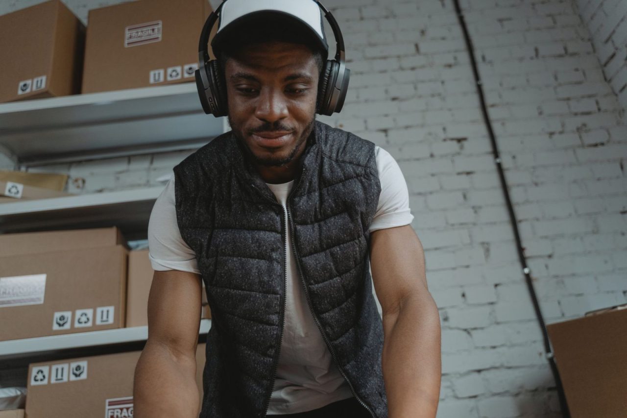 Warehouse employee wearing headphones organizing packages at a packing station