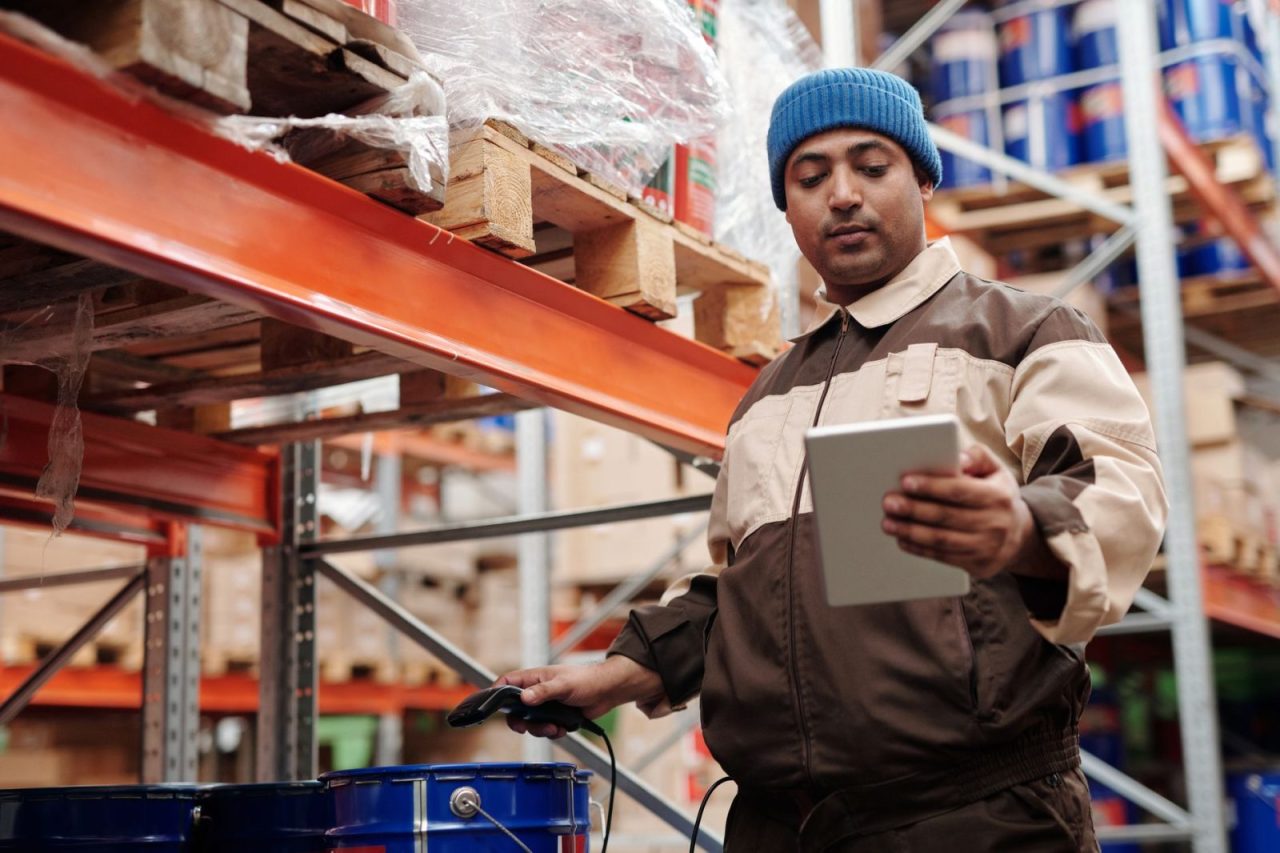 Warehouse employee scans items with a tablet to check inventory accuracy