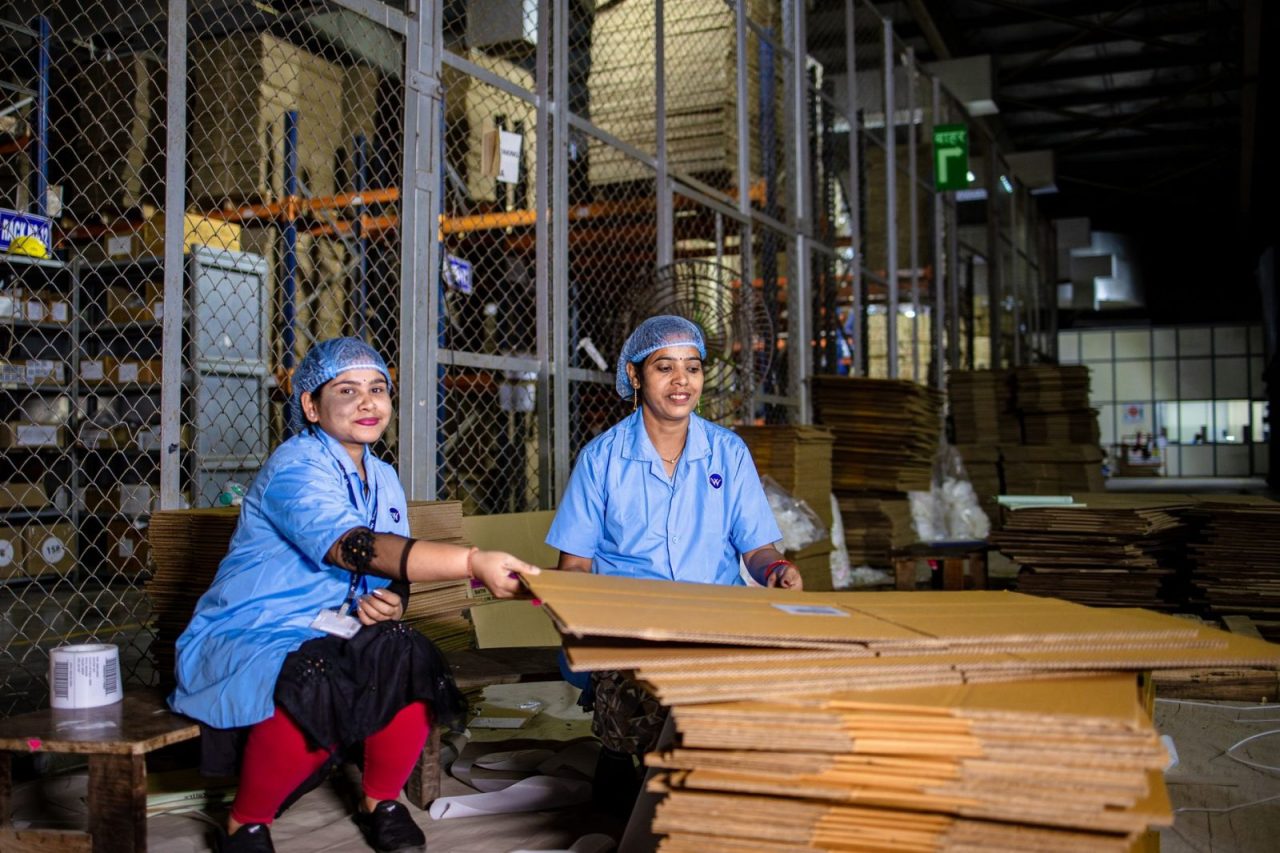 deux femmes en uniforme manipulent du carton dans un entrepôt industriel