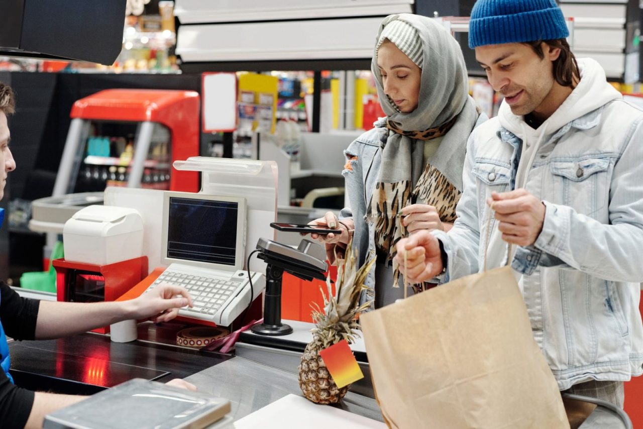 un couple moyen-oriental paie à la caisse d'un supermarché avec un smartphone