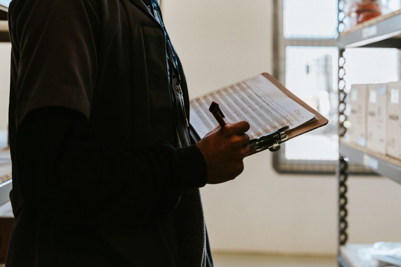 Industrial worker managing inventory in a warehouse with a clipboard and checklist