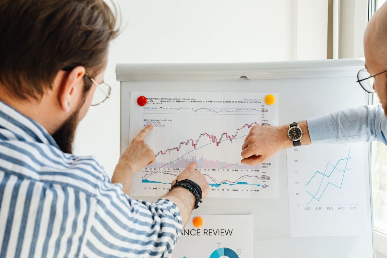 Colleagues reviewing data trends on a whiteboard with graphs and charts