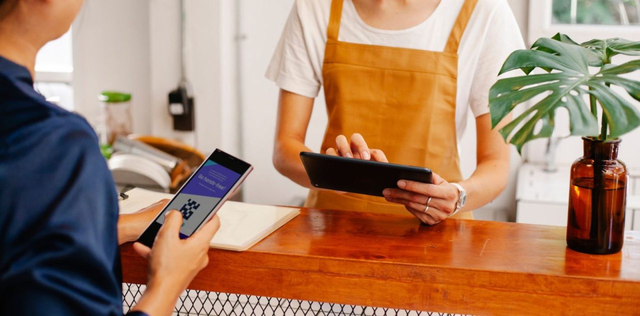 personne utilisant une application sur smartphone et collaborant avec un partenaire sur une tablette au comptoir d'une