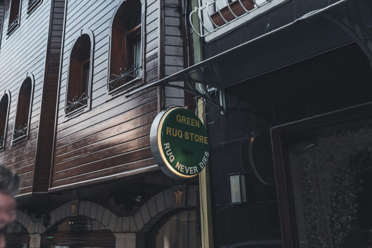 City street with a wooden building facade and a rug store sign