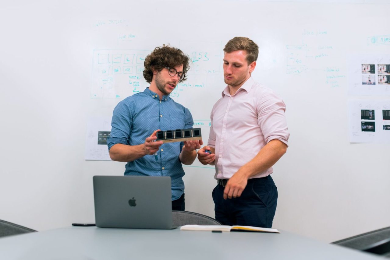 Two men in an office discussing a tech prototype