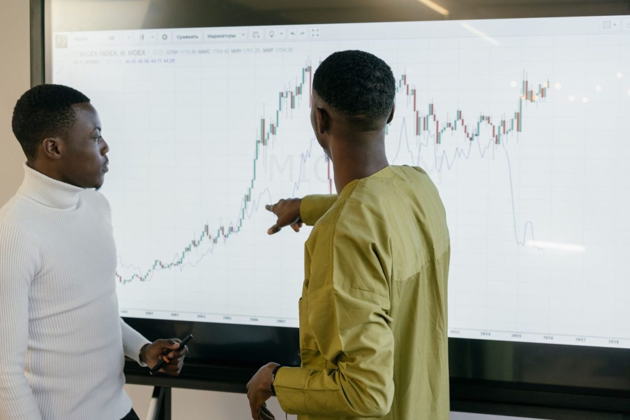 Two professionals discussing financial trends on a graph at an office desk