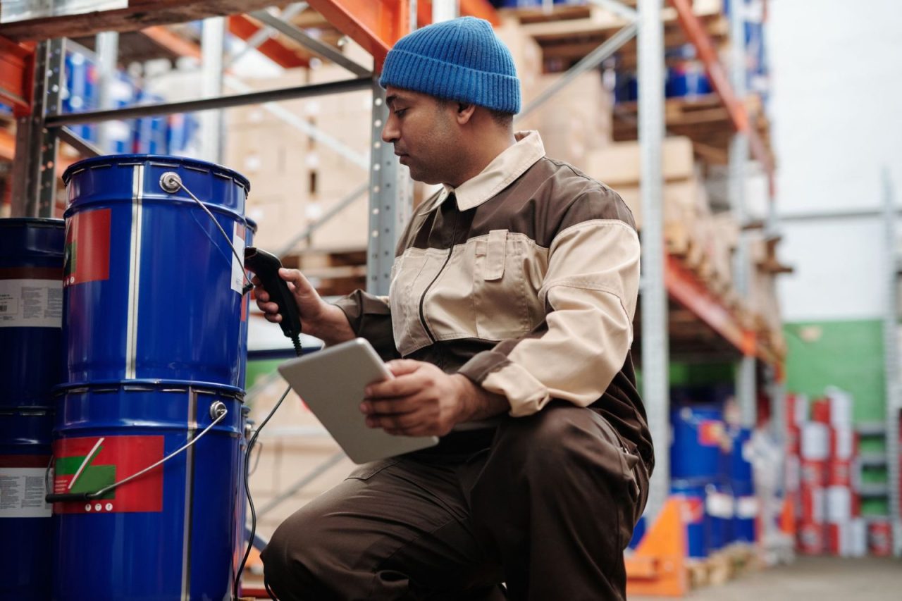 Warehouse employee scanning inventory with a tablet and scanner in an industrial storage area