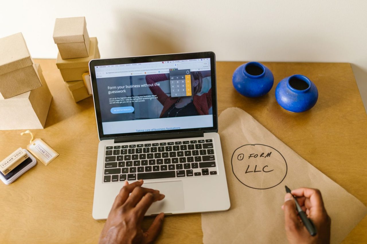 Workspace with laptop, packaging materials, and handwritten LLC notes for a small business startup
