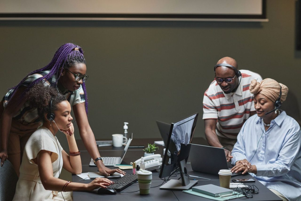 Team of professionals collaborating in a modern office using headsets and computers