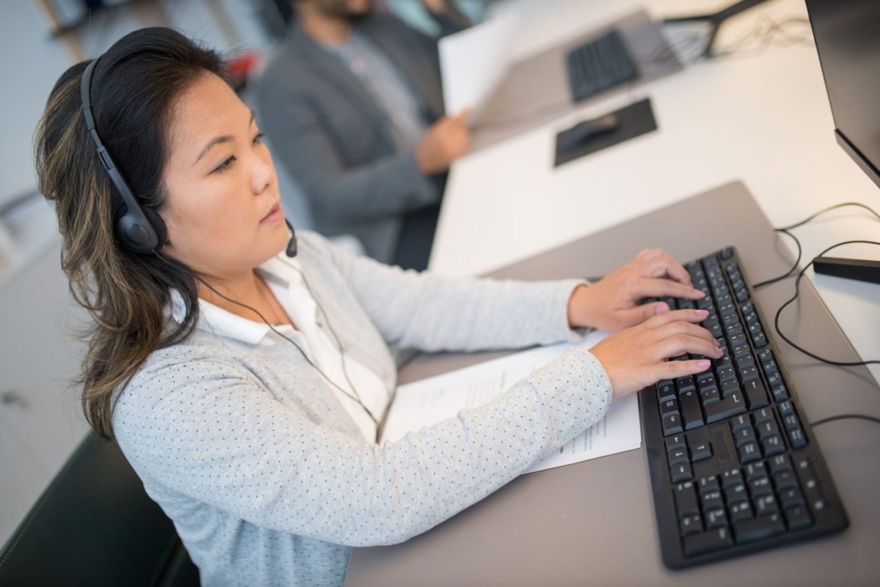 Woman with headphones working at a computer in an office