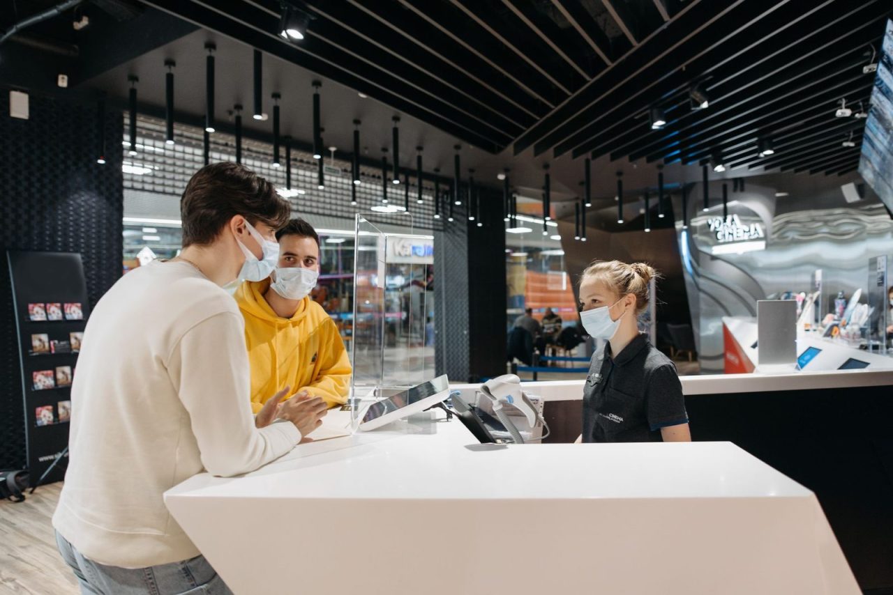 Masked customers and staff interacting at a store checkout counter