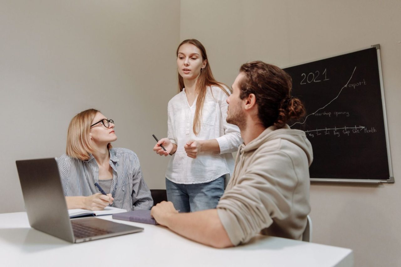 Co-workers having a group discussion around a desk in an office setting