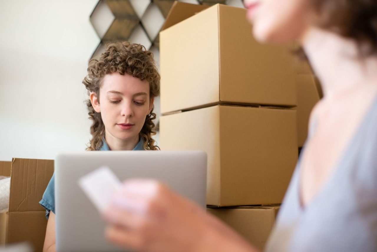 Women managing online orders with cardboard boxes and a laptop in a small business