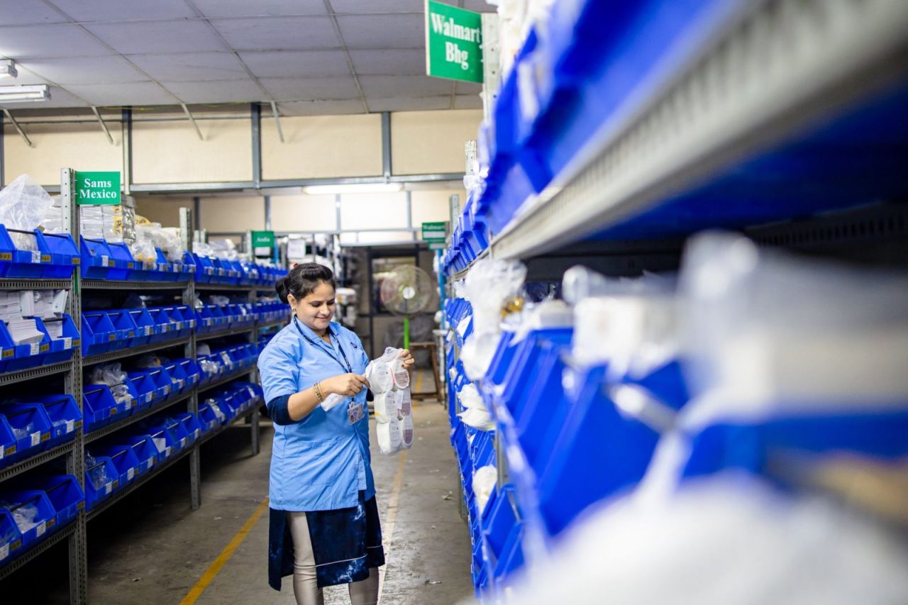 Worker organizes shelves in a warehouse with labeled storage bins