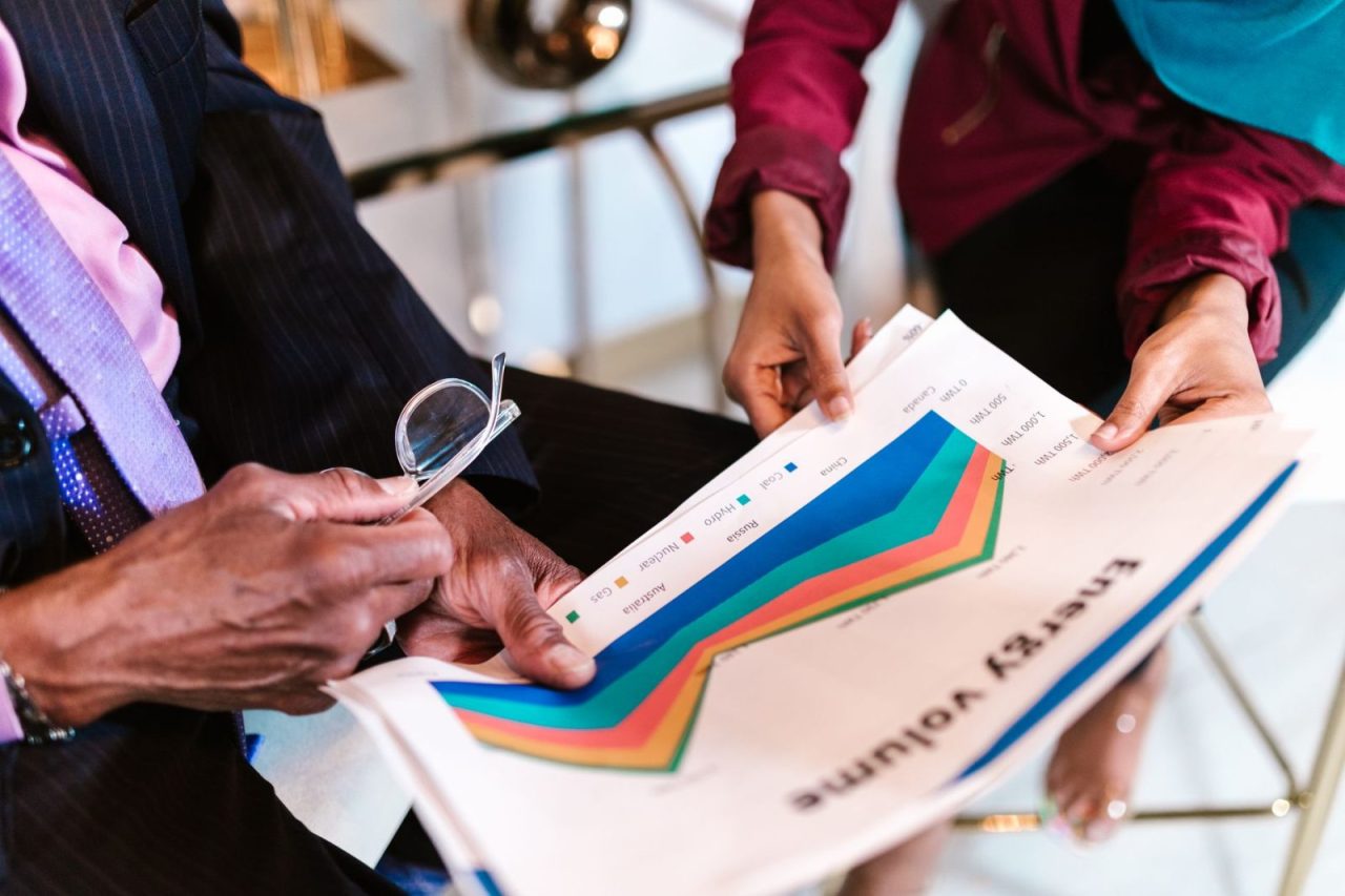 Two professionals review detailed energy consumption charts in an office