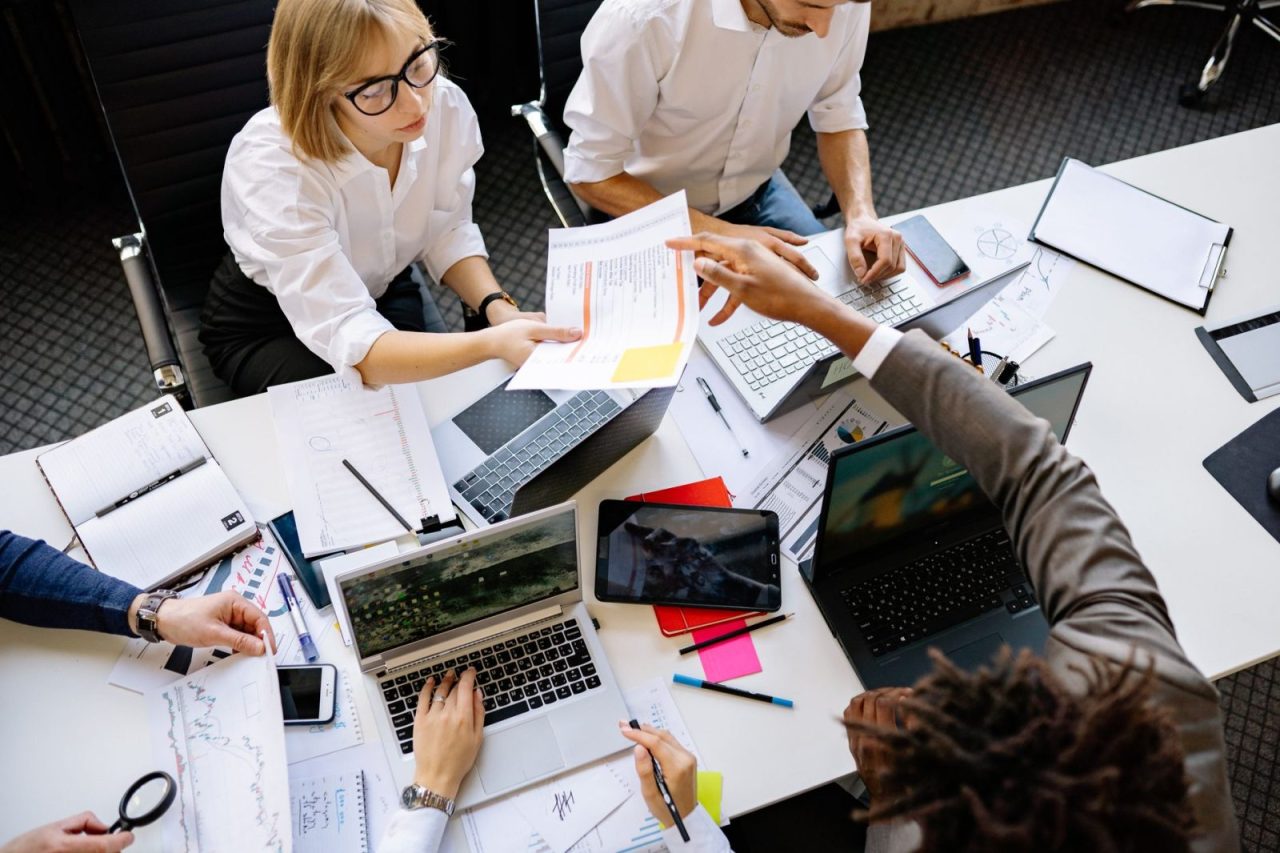 Team collaborating around laptops and documents in a modern office setting