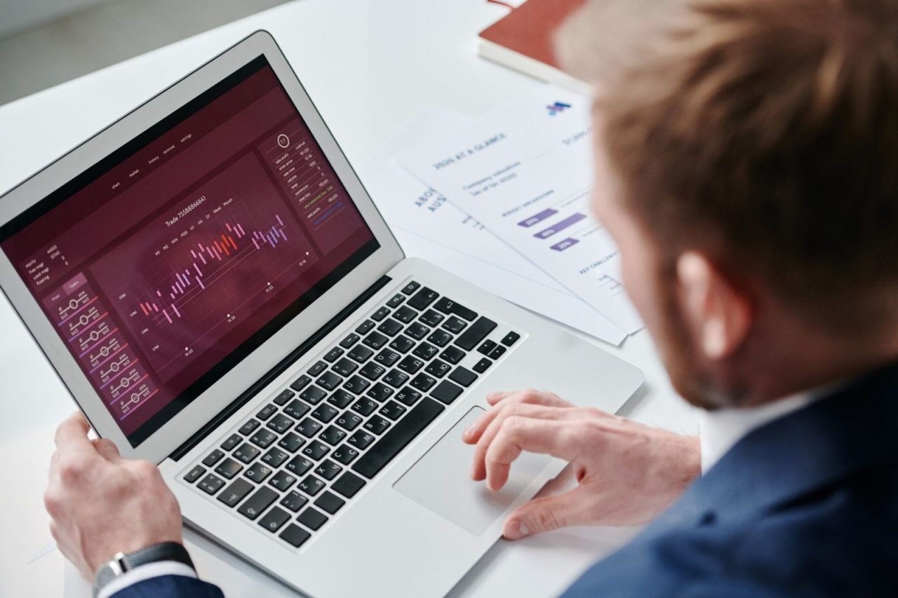 Person analyzing data analytics dashboard on a laptop in a well-lit office