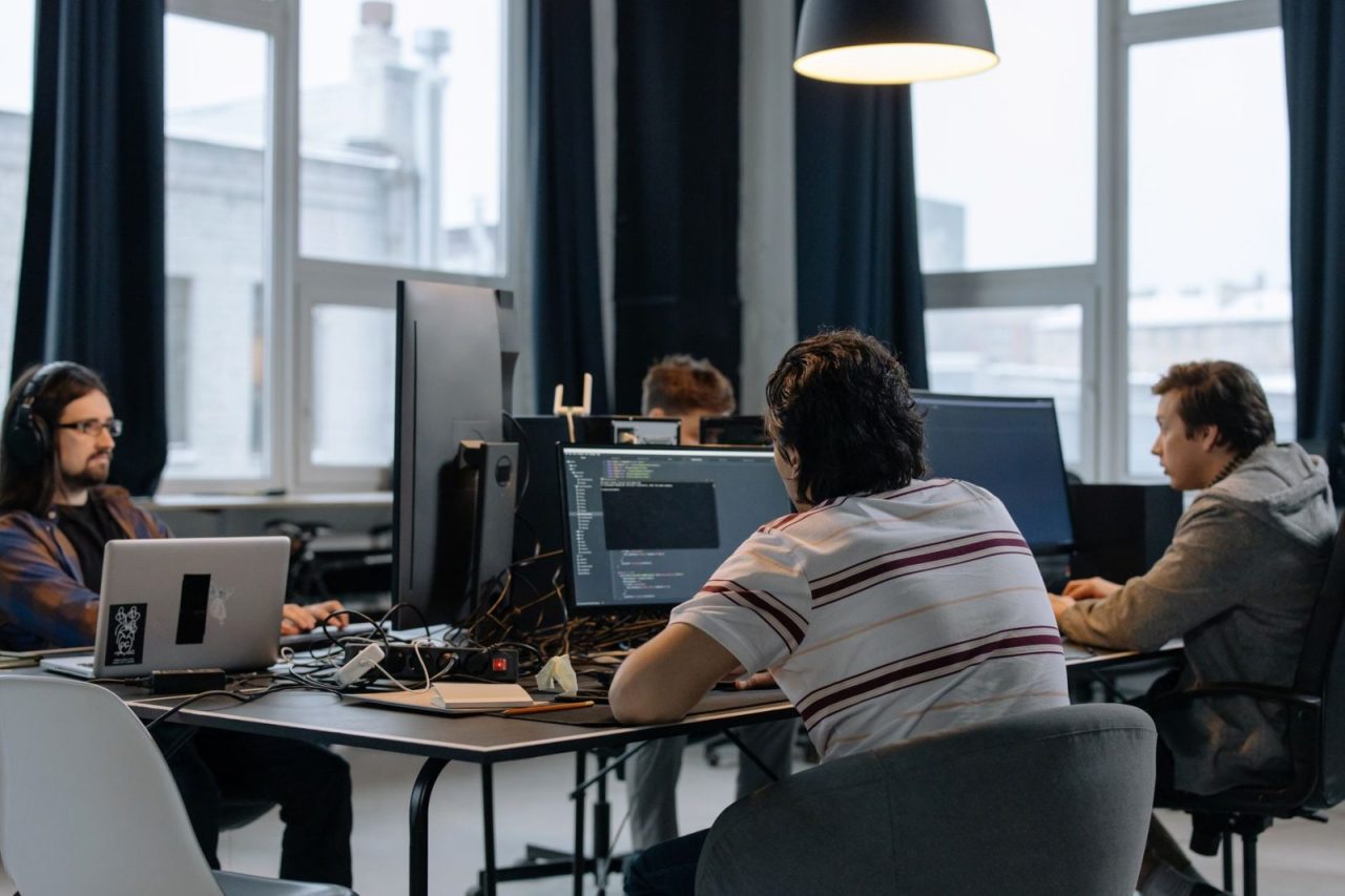 Developers collaborating at computers in a modern tech office workspace