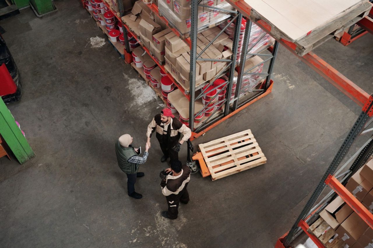 Workers discussing logistics among packages in a warehouse