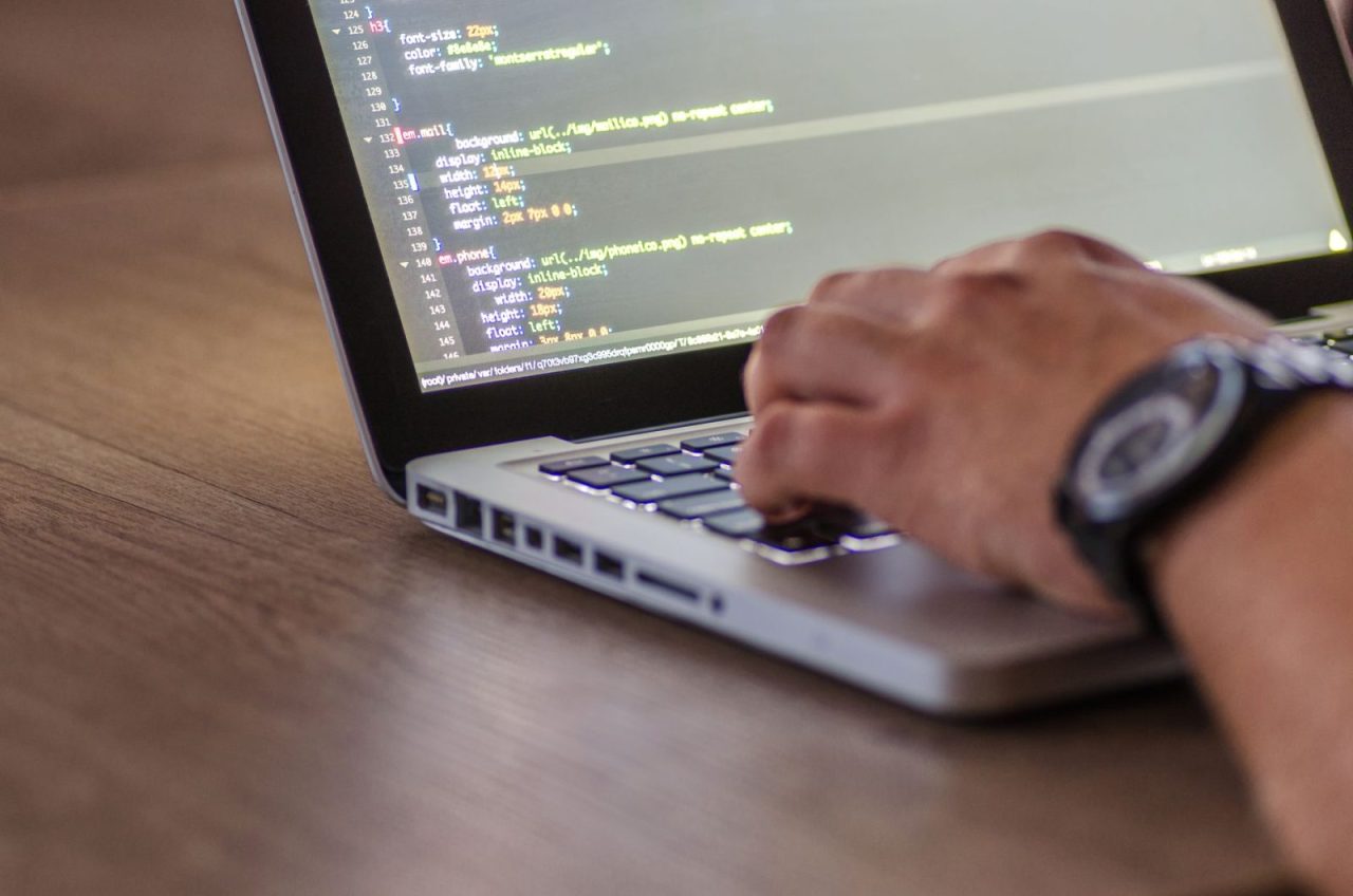 Hands typing code on a laptop with the screen in focus