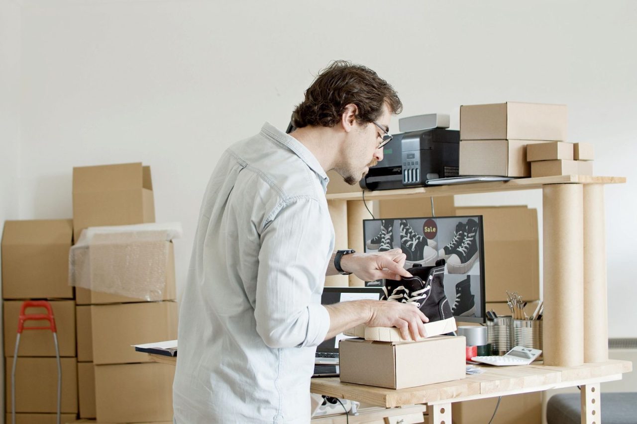 Businessman packing shoes into a cardboard box for an online store order