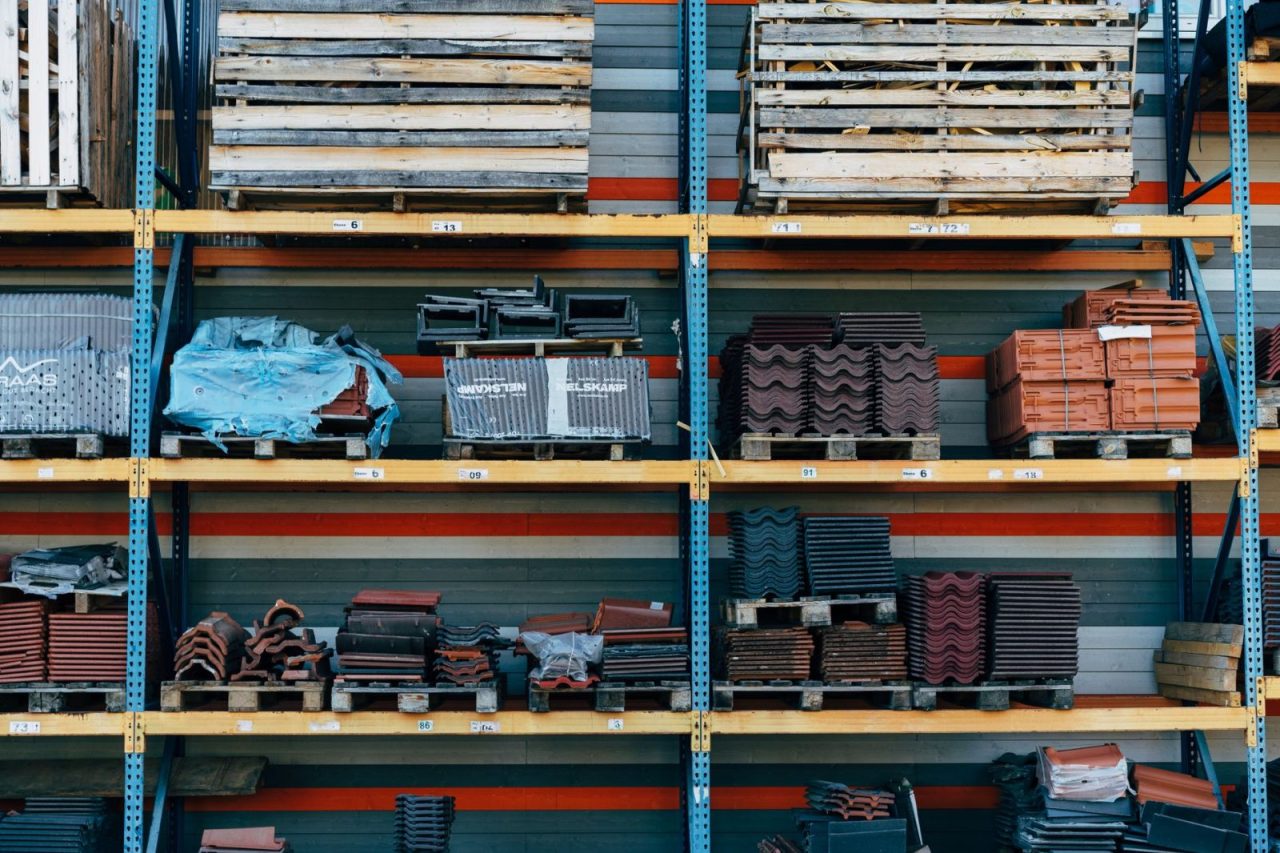 Shelves stocked with construction materials such as tiles and wood pallets in a warehouse