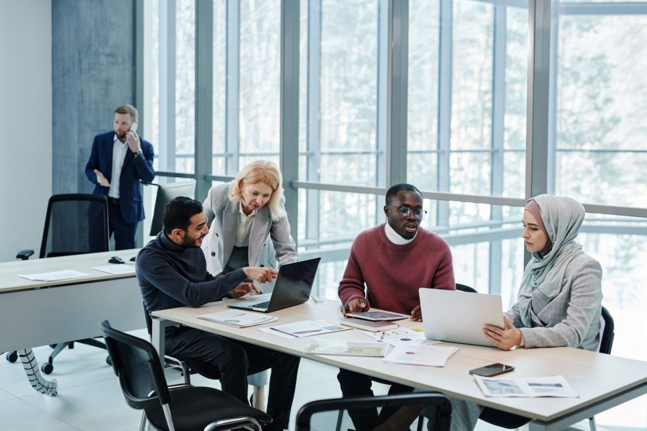 Group of professionals collaborating around laptops in a modern office